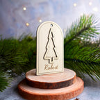 Étiquette cadeau en bois au prénom Robert posée sur un rondin