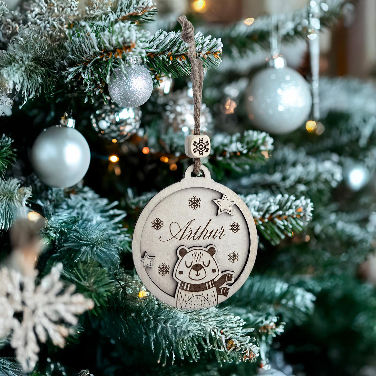 Boule de Noël en bois au prénom Arthur et ourson suspendue dans un sapin