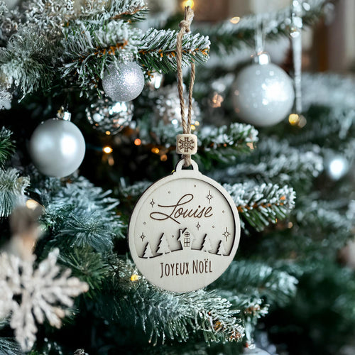 Boule de Noël en bois au prénom Louise suspendue dans un sapin